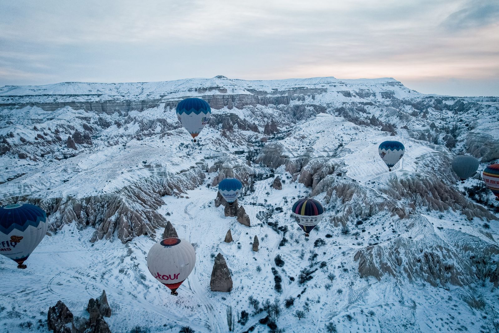 Balon udara melayang di atas lembah Cappadocia bersalju pada musim dingin